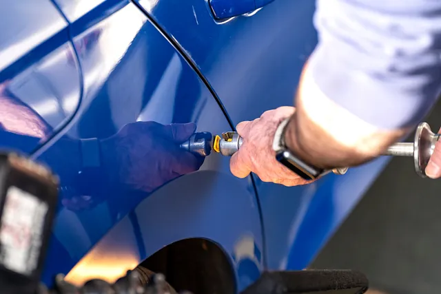 Eine Delle in einem blauen Auto wird mithilfe von Smart Repair in Bergisch Gladbach entfernt. 